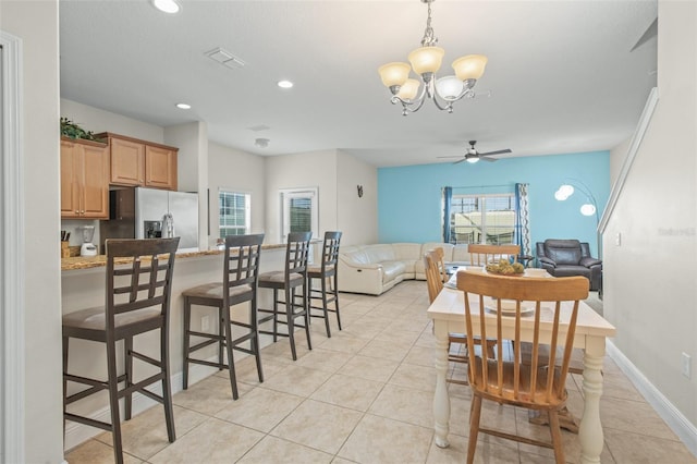 tiled dining space with ceiling fan with notable chandelier