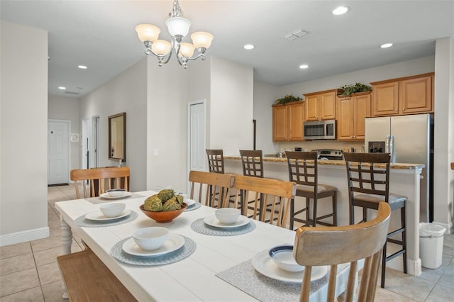 dining area with light tile patterned floors and an inviting chandelier