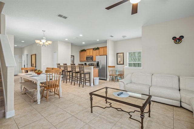 tiled living room featuring ceiling fan with notable chandelier