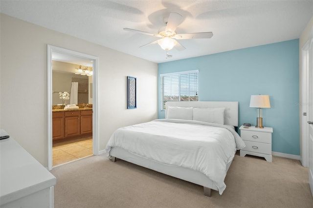 bedroom with connected bathroom, light colored carpet, and ceiling fan