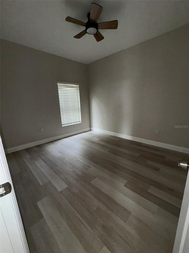 unfurnished room with dark wood-type flooring and ceiling fan