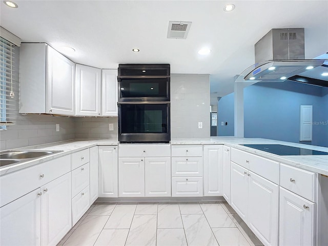 kitchen with white cabinets, light stone counters, island range hood, backsplash, and black electric stovetop