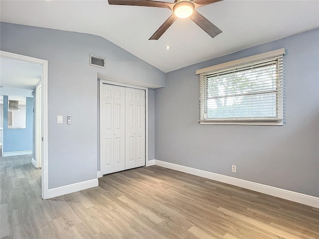 unfurnished bedroom with ceiling fan, light hardwood / wood-style flooring, vaulted ceiling, and a closet