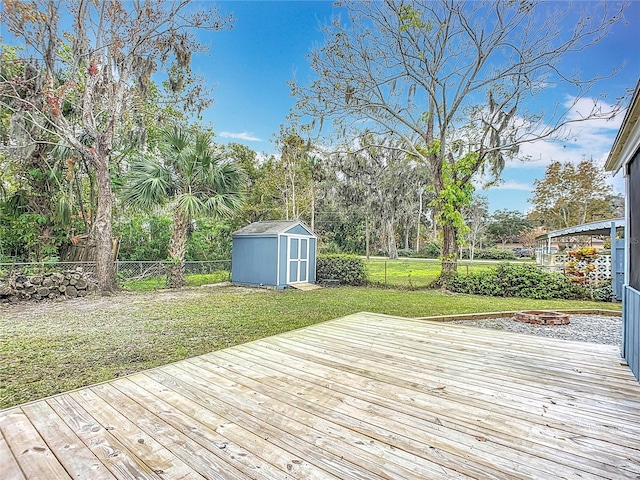 deck with a lawn, a fire pit, and a storage shed