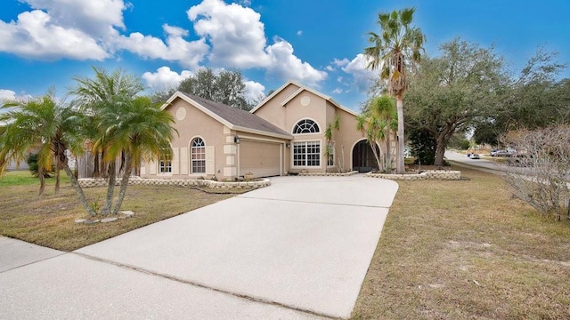 view of front of house featuring a garage, driveway, a front yard, and stucco siding