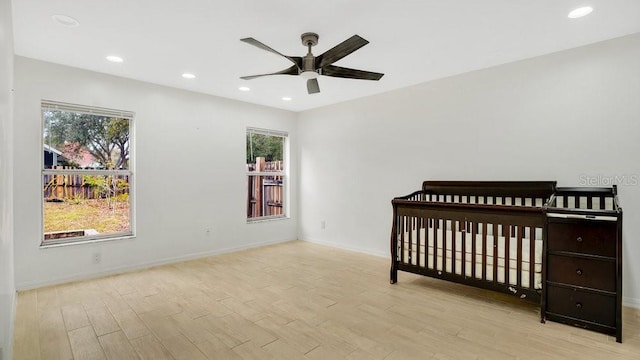 bedroom featuring ceiling fan, a nursery area, and multiple windows