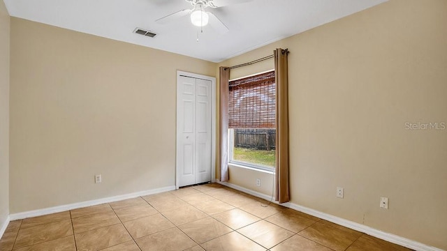 tiled spare room featuring ceiling fan