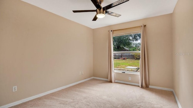 spare room with ceiling fan, plenty of natural light, and light colored carpet