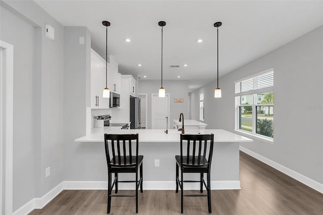 kitchen featuring kitchen peninsula, white cabinetry, a breakfast bar, decorative backsplash, and stainless steel appliances