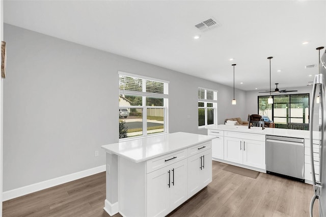 kitchen featuring light hardwood / wood-style flooring, pendant lighting, dishwasher, white cabinets, and a center island