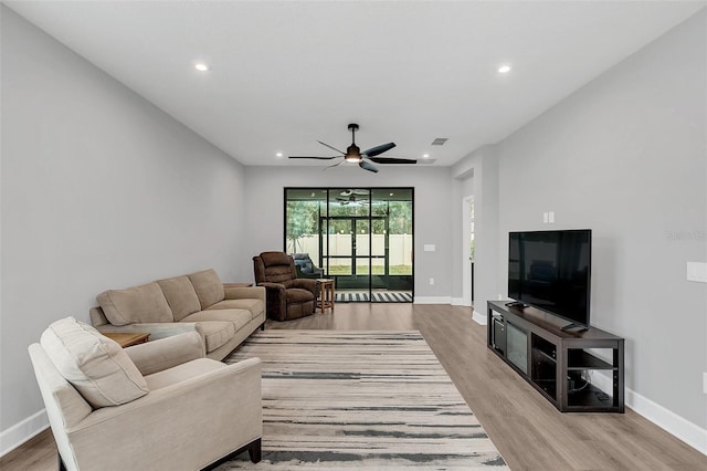 living room with ceiling fan and light hardwood / wood-style flooring