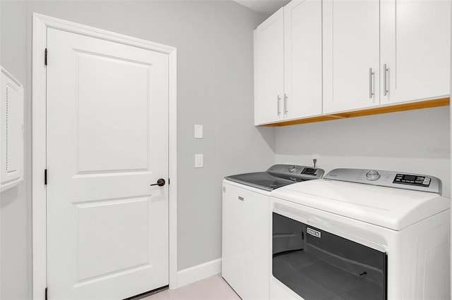 laundry room featuring light tile patterned floors, cabinets, and washer and clothes dryer