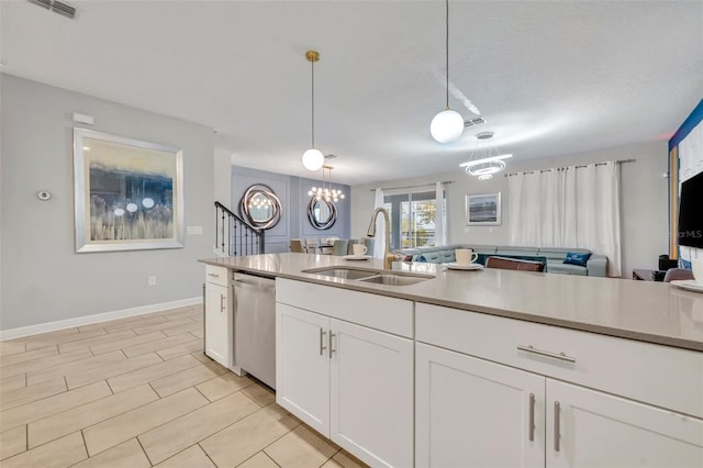 kitchen featuring sink, white cabinets, a textured ceiling, stainless steel dishwasher, and pendant lighting