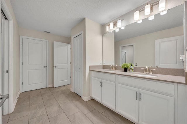 bathroom with a textured ceiling, tile patterned floors, and vanity