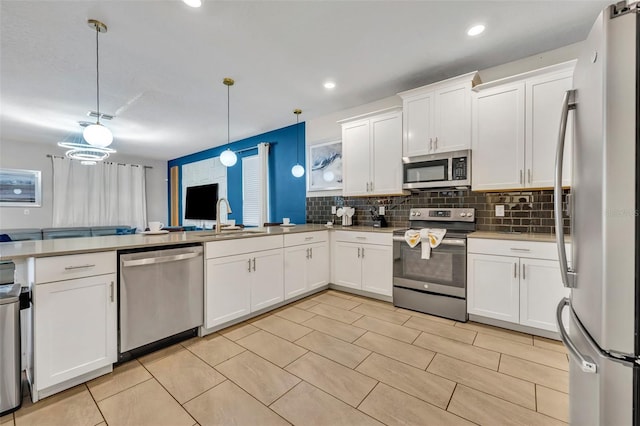 kitchen featuring decorative light fixtures, stainless steel appliances, decorative backsplash, white cabinetry, and sink