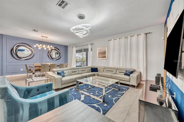 living room with an inviting chandelier, a textured ceiling, and light tile patterned floors