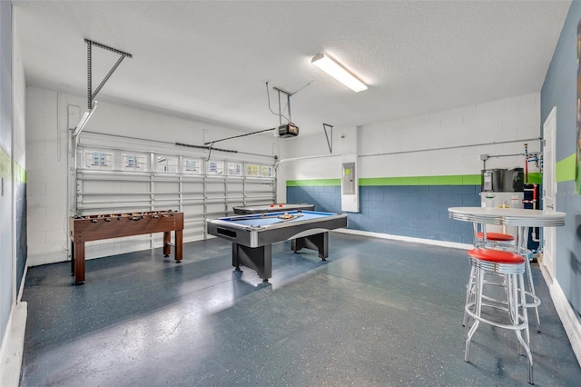 rec room with electric panel, a textured ceiling, heat pump water heater, and billiards