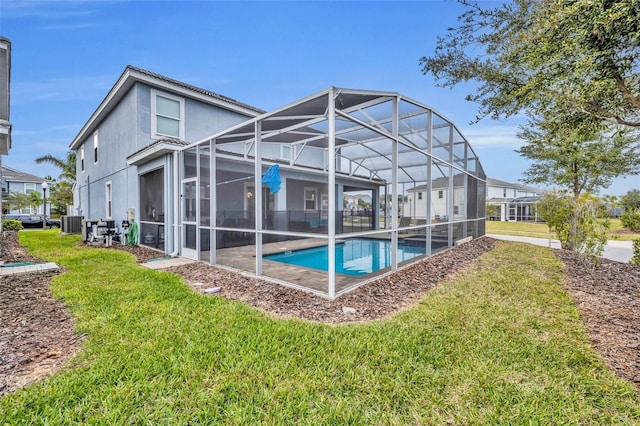 back of property with a yard, central AC, glass enclosure, and a patio area