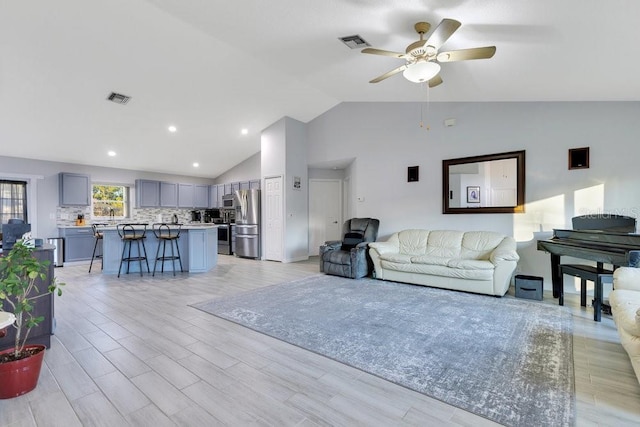 living room featuring ceiling fan, lofted ceiling, and light wood-type flooring