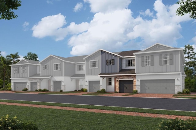 view of front of house with a garage, stone siding, decorative driveway, board and batten siding, and a front yard