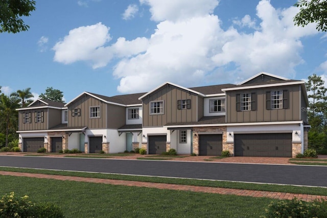 view of front of house with an attached garage, stone siding, driveway, a front lawn, and board and batten siding