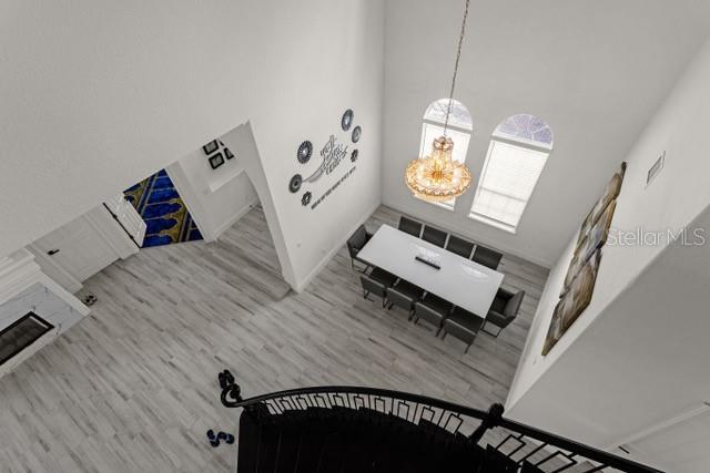 living room featuring wood-type flooring, a towering ceiling, and a notable chandelier