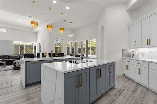 kitchen with hanging light fixtures, gray cabinets, a kitchen island, black electric stovetop, and white cabinets