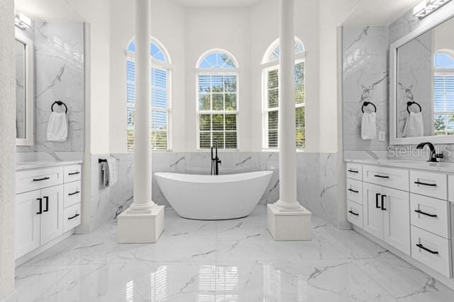 bathroom featuring vanity, decorative columns, and a washtub