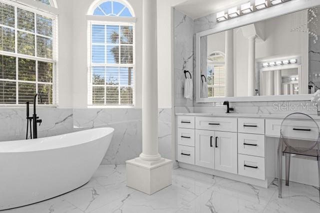 bathroom with vanity, a bathtub, decorative columns, and a healthy amount of sunlight