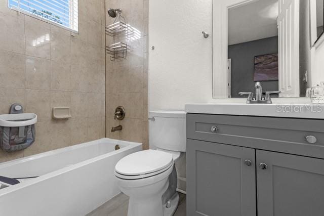 full bathroom featuring vanity, tiled shower / bath combo, and toilet