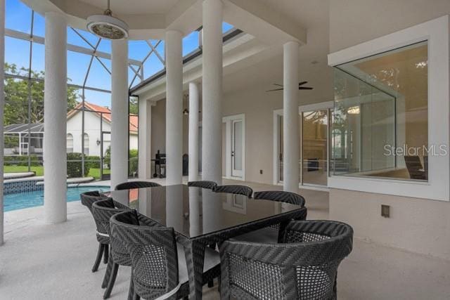 view of patio with ceiling fan and glass enclosure