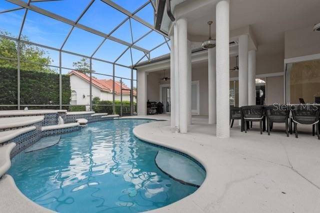 view of swimming pool with a patio, ceiling fan, and glass enclosure