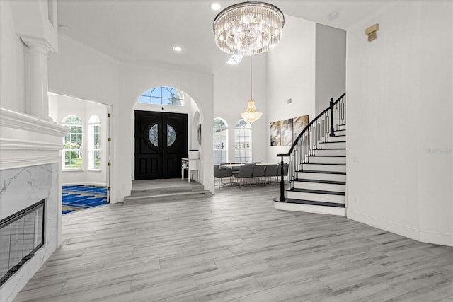 entrance foyer with a notable chandelier, a towering ceiling, and light wood-type flooring