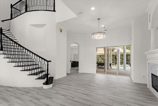 living room featuring light hardwood / wood-style flooring, a fireplace, a chandelier, and a high ceiling