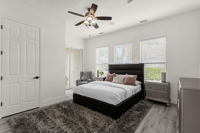 bedroom with multiple windows, wood-type flooring, and ceiling fan