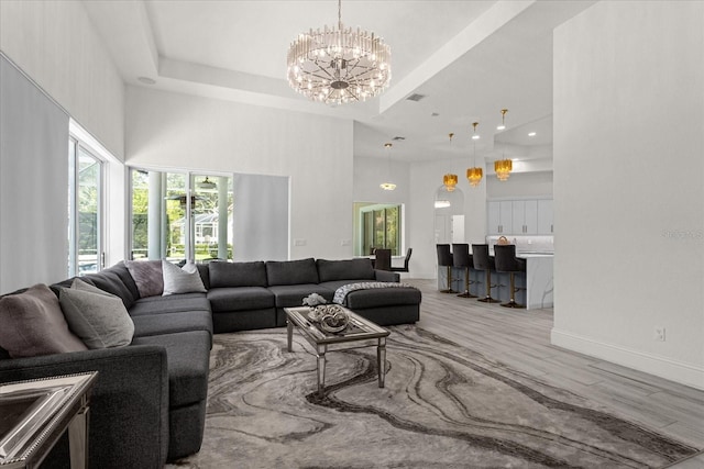 living room featuring a notable chandelier, a tray ceiling, hardwood / wood-style flooring, and a towering ceiling