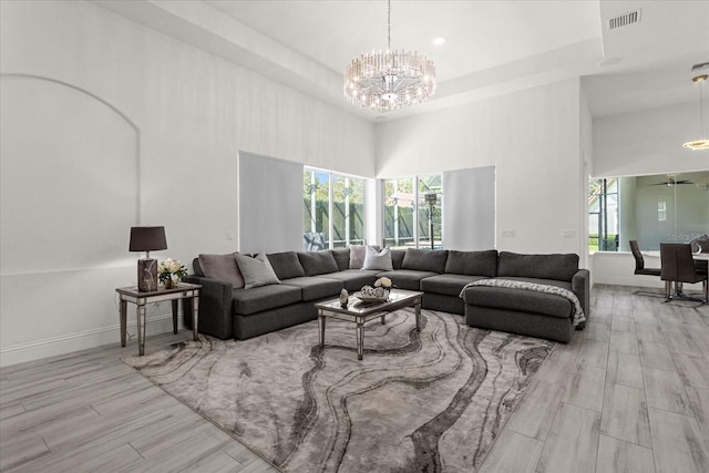 living room featuring a notable chandelier, plenty of natural light, a high ceiling, and light wood-type flooring