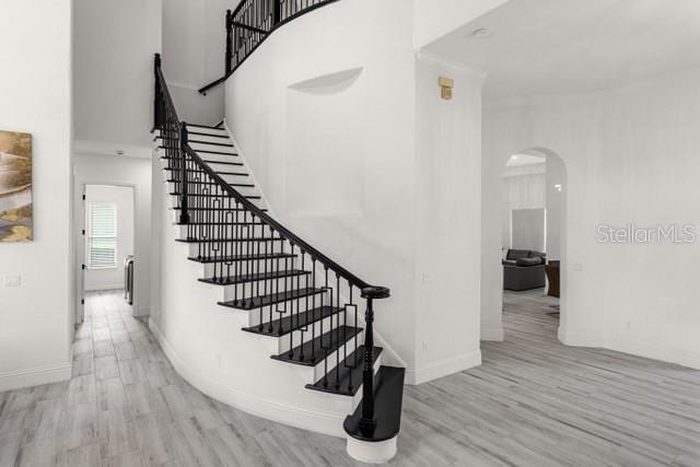 staircase featuring wood-type flooring and a high ceiling