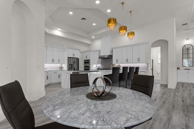 dining area featuring light hardwood / wood-style floors and a high ceiling