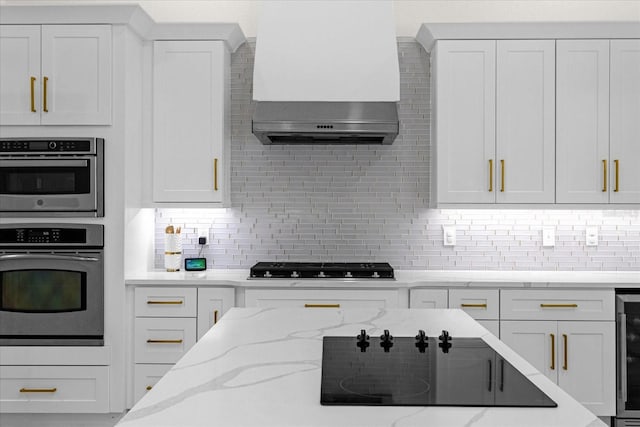 kitchen with white cabinetry, light stone countertops, black gas cooktop, and decorative backsplash