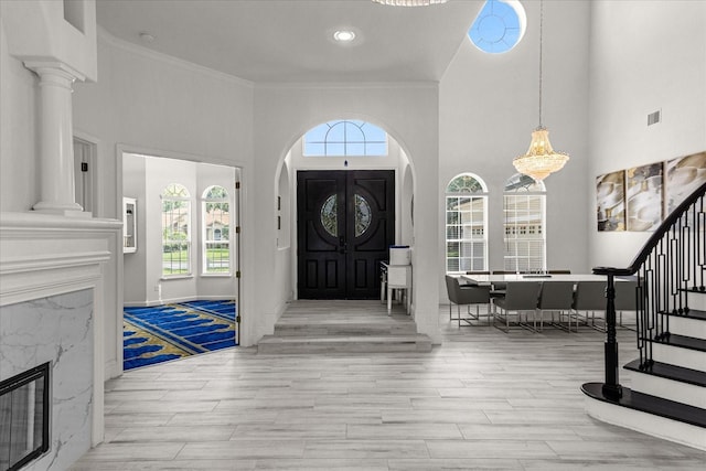 foyer entrance with ornamental molding, a high ceiling, and light wood-type flooring