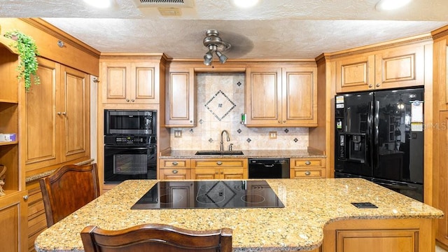 kitchen with black appliances, a breakfast bar, light stone counters, decorative backsplash, and sink