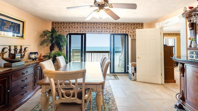 dining space featuring ceiling fan and a water view