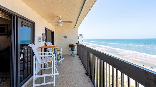 balcony with ceiling fan, a view of the beach, and a water view