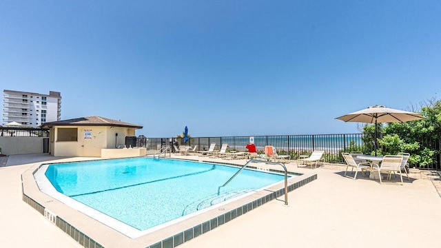 view of swimming pool featuring a water view and a patio area