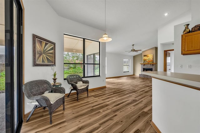 sitting room with ceiling fan, lofted ceiling, a fireplace, and light hardwood / wood-style flooring