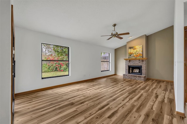 unfurnished living room featuring vaulted ceiling, ceiling fan, a fireplace, and light wood-type flooring