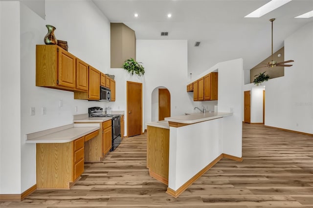 kitchen with high vaulted ceiling, electric range, a skylight, and ceiling fan