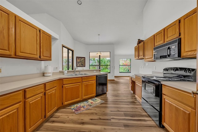 kitchen featuring black appliances, decorative light fixtures, sink, and light hardwood / wood-style flooring