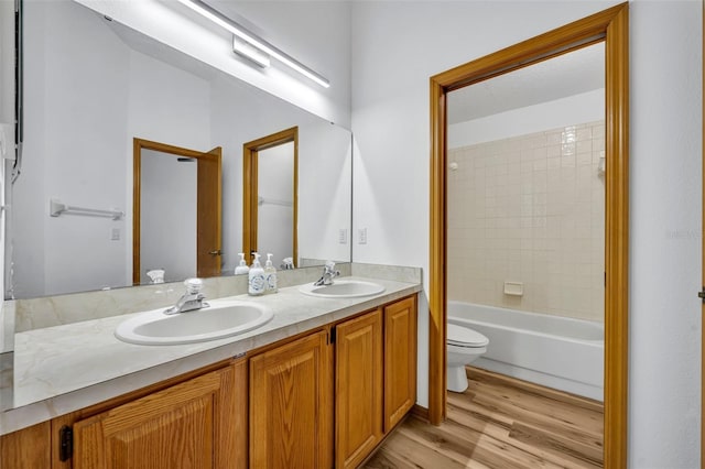 full bathroom with toilet, vanity, tiled shower / bath combo, and hardwood / wood-style flooring